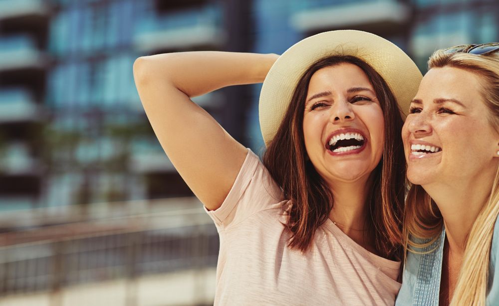 Two women smiling together on sunny day, copy space