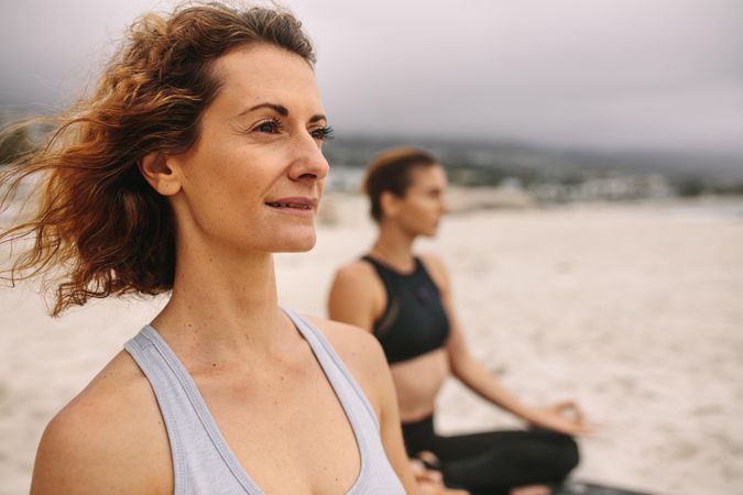 Women in fitness wear at the beach doing yoga on a cloudy day