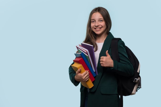 Teen girl with backpack, smiling and giving thumbs-up