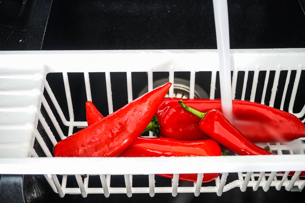 Fresh red pepper being cleaned in sink
