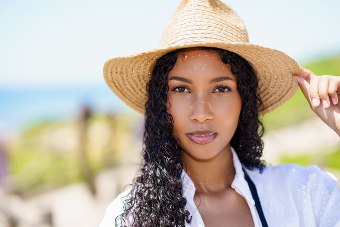 A Beautiful Sunlit Portrait of a Young Woman Wearing a Stylish Straw Hat at the Beach