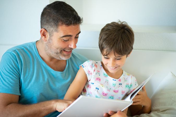 Dad with girl reading in bed