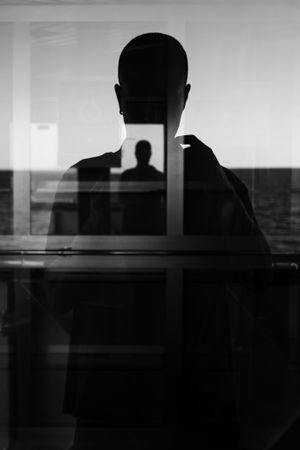 Silhouette of man taking picture in window with reflection