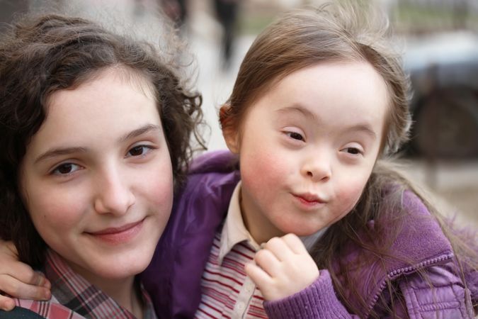 Two sisters close together outside on a cold day