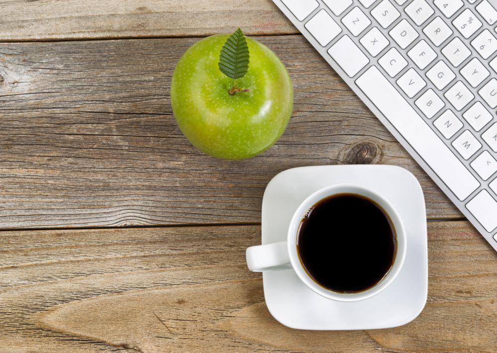 Apple and coffee with computer keyboard for school or office on rustic wooden boards