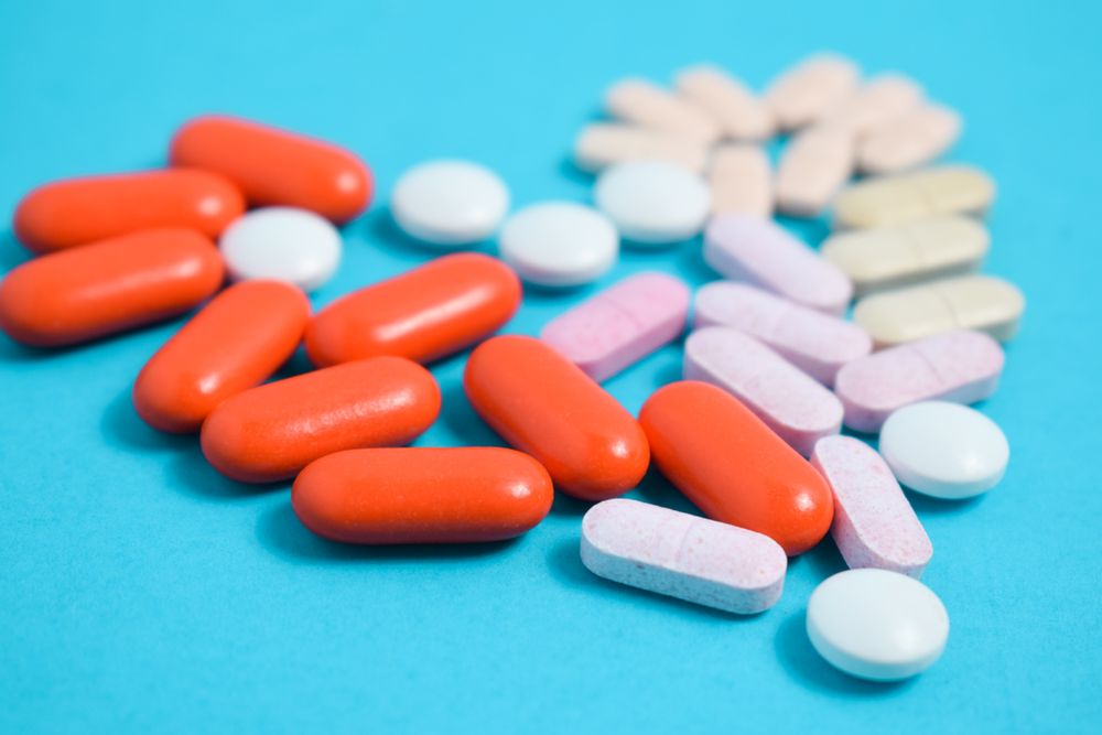 Variety of pIlls in heart shape on blue background