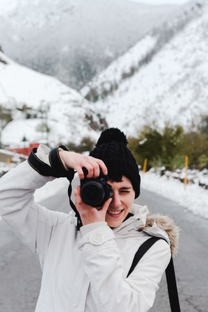 Content woman taking picture in snowy mountains