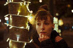 Young woman near tree with fairy lights