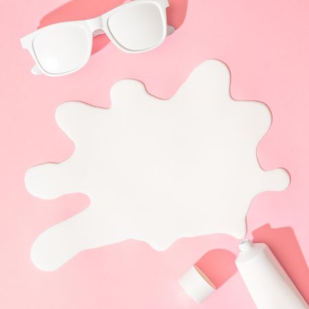 Sunglasses and sunscreen on pastel pink background