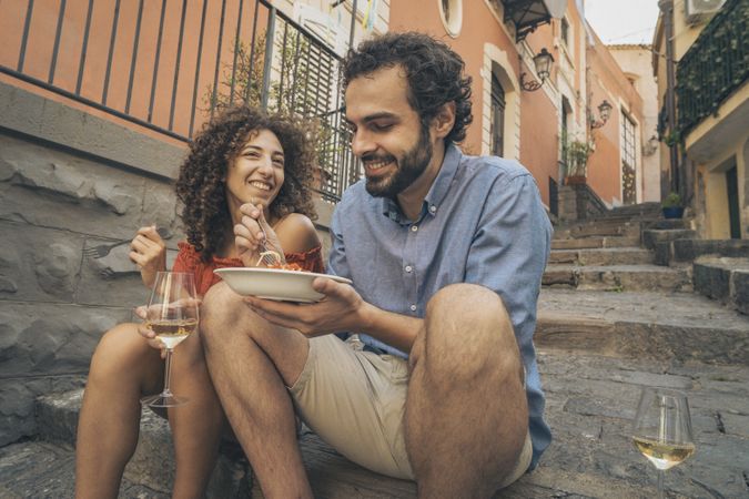 Young couple smiling while sharing a plate of pasta in Italy.