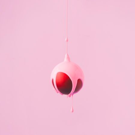 Red Christmas bauble decoration with pastel pink paint dripping