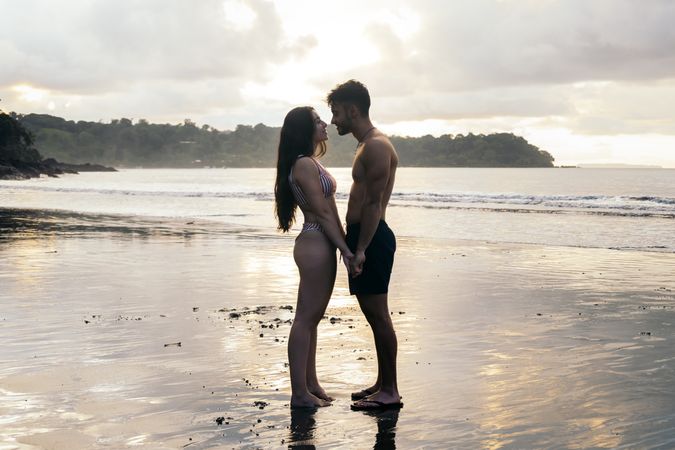 Young couple standing on the beach at sunset