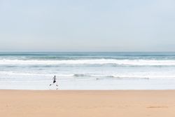 Sportsman in active wear jogging on lonely beach