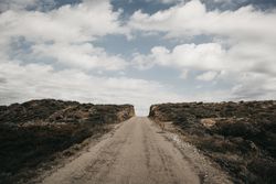 Cloudy sky over hill with road