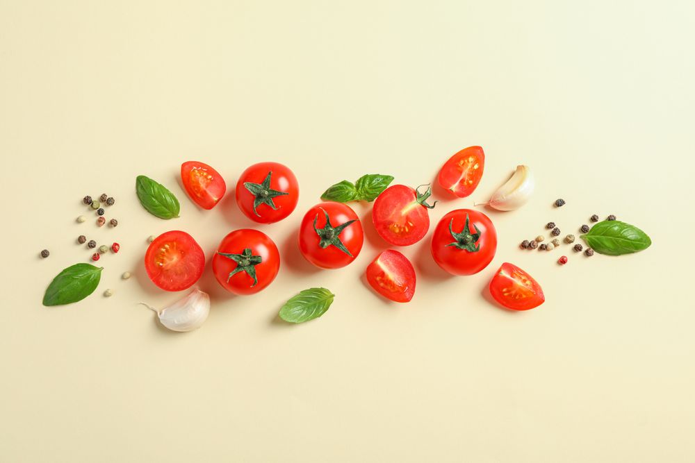 Flat lay composition with fresh cherry tomatoes, pepper, garlic and basil on color background, space for text. Ripe vegetables