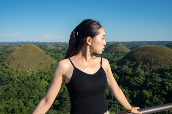 Happy woman standing on observation deck on hill