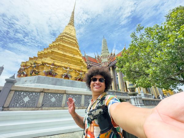 Tourist takes a selfie with a beaming smile in a historic golden temple in Asia.