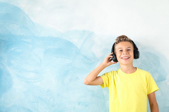 Boy with headphones against color background, space for text