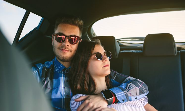 Young couple resting in the backseat of the car