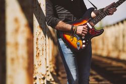 anonymous Man with guitar standing on bridge
