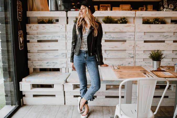 Casual stylish woman standing at table in cafe