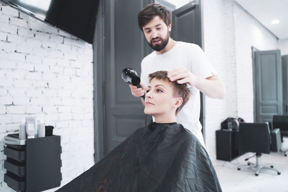 Hairdresser drying hair to woman