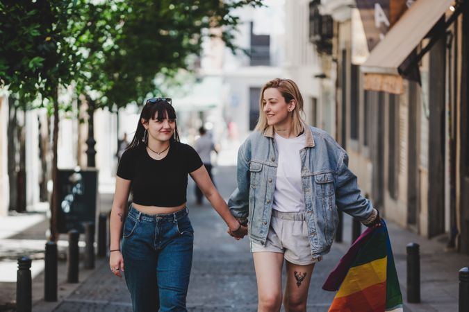 Lesbian couple with LGBT flag walking on street