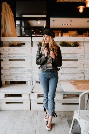 Casual stylish woman standing at table in cafe