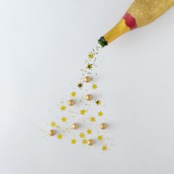 Gold champagne bottle pouring glitter into the shape of a Christmas tree
