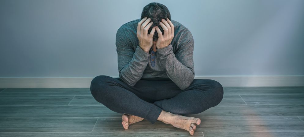 Man with problems covering face sitting on the floor