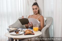 Woman reading magazine during breakfast 4OqXJ0