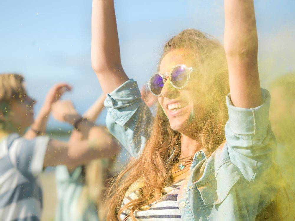 Close-up Portrait of a Young Woman with Sunglasses Standing in the Crowd of People Celebrating Holi Festival.