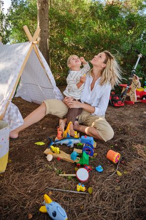 Happy woman and boy playing together near tent