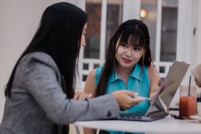 Collaborative Businesswomen Sharing Ideas at Cafe with Laptop