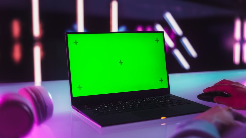 Anonymous Content Creator Using a Laptop Computer with Mock Up Green Screen Chromakey Display with Motion Tracker Placeholders. Photo Template for Gamers, Computer Products and Software