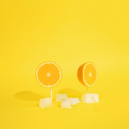 Orange halved on toothpicks and ice cubes