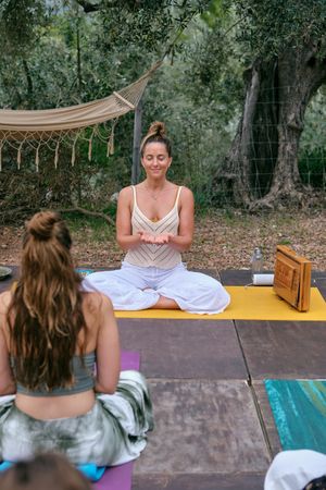Calm woman practicing yoga with class in nature