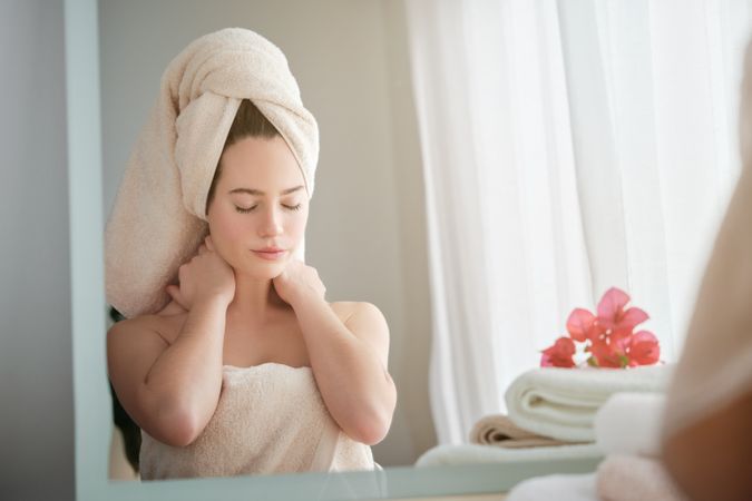 woman with eyes closed sitting in front of mirror