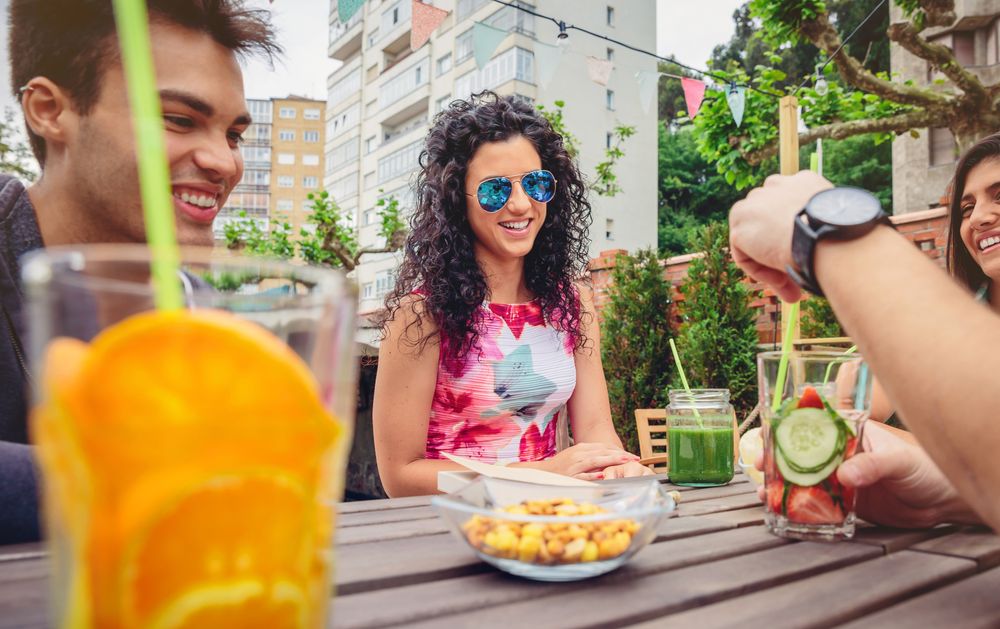 Male and female friends sitting outside with drinks and snacks