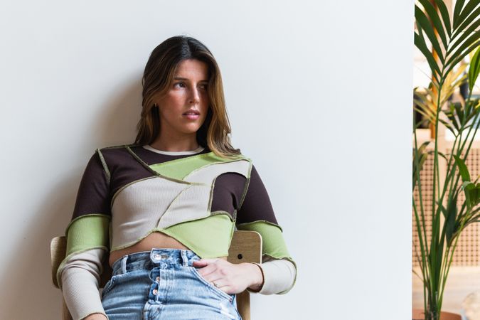 Gentle woman with hand in pocket resting on chair
