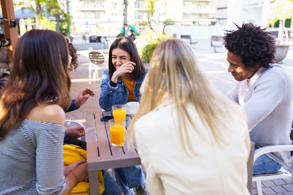 Woman laughing with her friends at an outside table