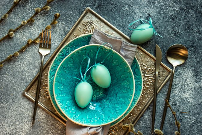 Top view of Easter holiday table setting with teal bowl and teal decorative eggs