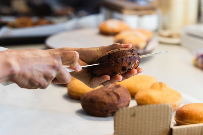Crop cook cutting sponge cake in bakery