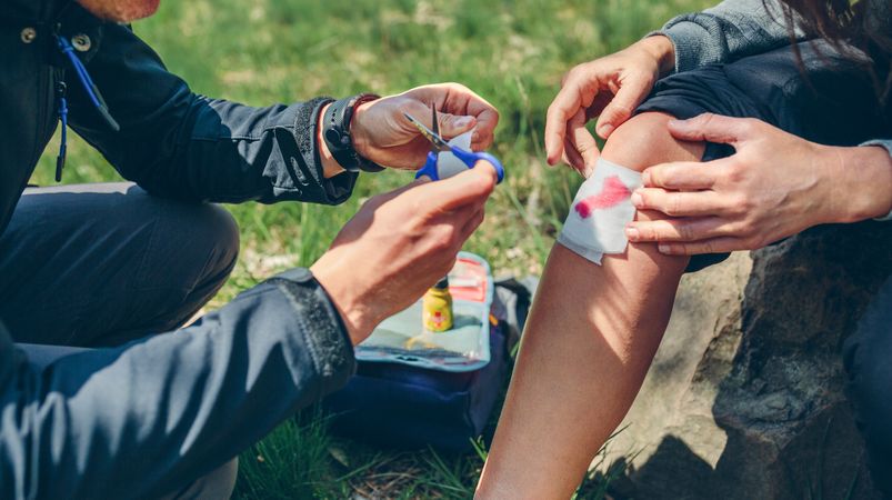 Man healing knee to woman who has been injured trekking
