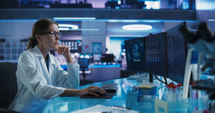 Hospital Research Laboratory: Female Medical Scientist Using Computer with Brain Scan MRI Images.