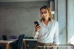 Smiling businesswoman using phone in office bxdRjb