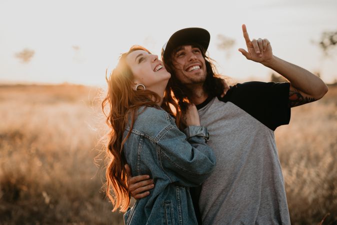Hipster couple bonding on field in sunlight