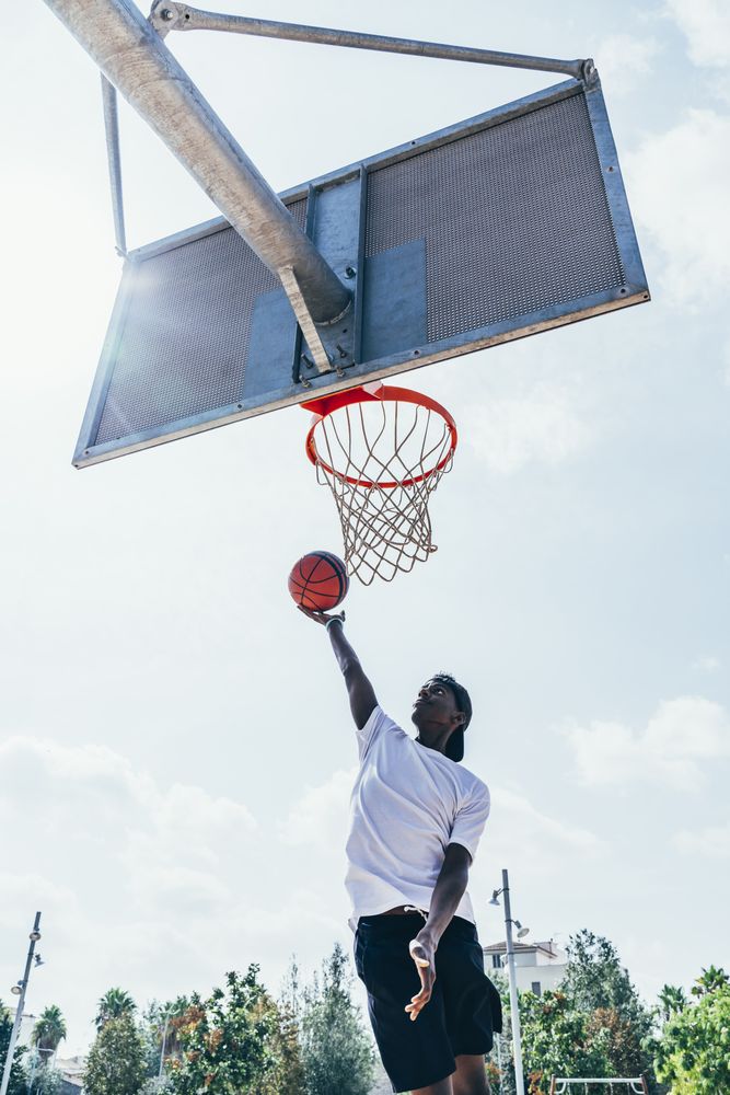 Black sportsman hanging on basketball lap