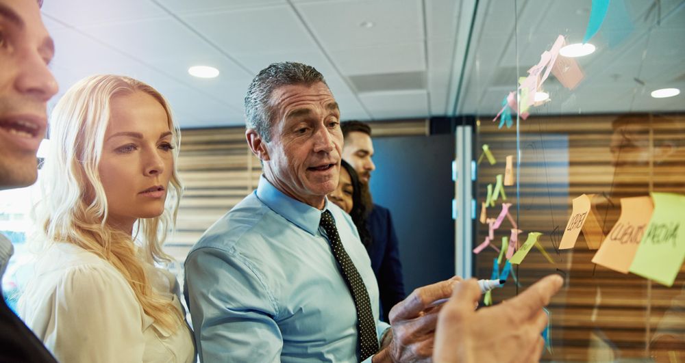 Group of people in business attire brainstorming with sticky notes