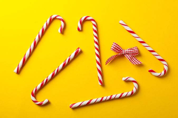 Composition with sweet candy canes on color background, space for text